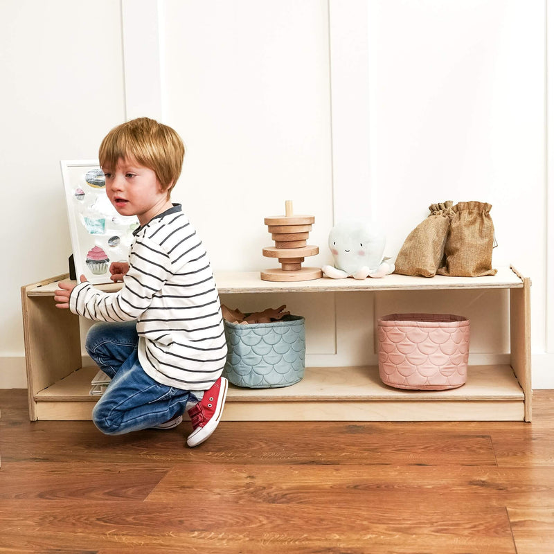 boy arranging his toys on his little toy shelf